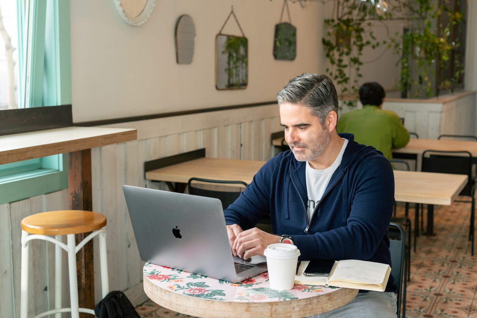 man in blue sweater sitting by the table using macbook